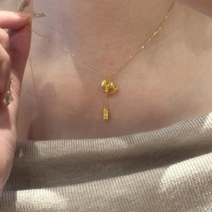 Detailed close-up of 24K gold plated necklace with rocking horse and bar pendant