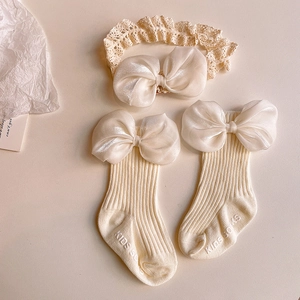 Detailed shot of baby socks and lace headband set with large cream satin bows