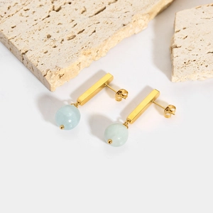 Close-up of 18k gold earrings with rectangular bars and light blue natural stone beads