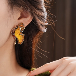 Detailed view of vintage butterfly earring with orange crystals and enamel finish