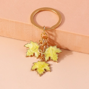 Detailed shot of golden metal keychain with three vibrant yellow enamel maple leaf charms