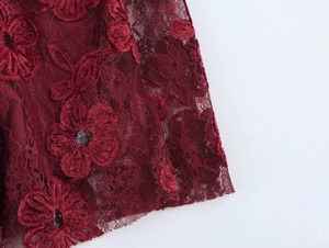 Detail of dark red jacquard lace fabric with velvet flowers and sequin accents