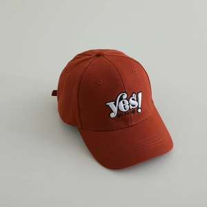 Close-up of caramel cotton baseball cap featuring white 'Yes!' letter embroidery detail