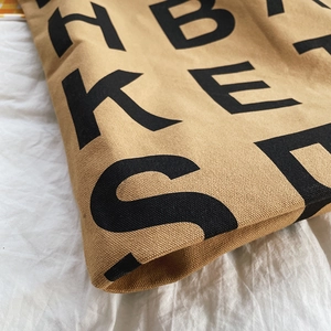 Close-up of khaki canvas tote bag featuring black letter print and durable fabric texture