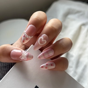 Detail of pink almond press-on nails with 3D bows, strawberry patterns and pearls