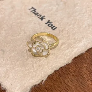 Detailed close-up of a camellia flower ring with white pearl center on textured paper