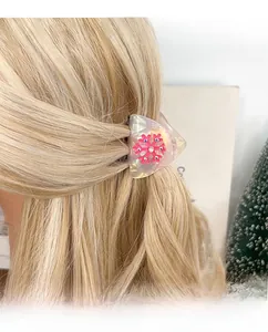 Close-up of a pearlescent triangle hair claw clip with a pink snowflake and rhinestones