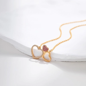 Macro shot of 18K gold plated necklace with three interconnected hearts and zircons