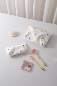 Close-up of white fabric cosmetic bags with colorful polka dots and zipper closure