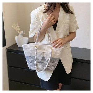 Detailed shot of color-block woven tote bag featuring a large white bow and rope handles