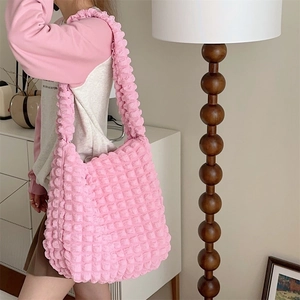 Detail of a bright pink popcorn texture tote bag worn by a model in a minimalist room