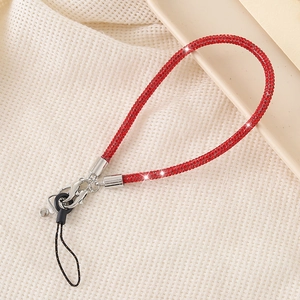 Close-up of a red rhinestone phone lanyard with metal clip on beige textured fabric