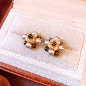Detailed close-up of 18k gold plated flower stud earrings with champagne pearls and zircons