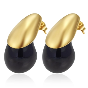Detail of gold-tone teardrop stud earrings with black resin droplets on white background