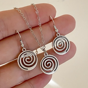Gros plan sur un ensemble collier et boucles d'oreilles fleur spirale en argent