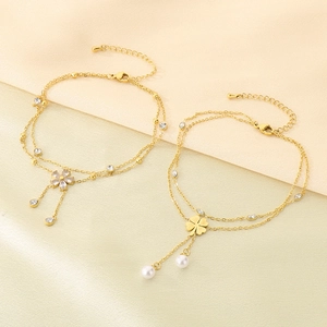 Close-up of double-layered gold clover and flower anklets with pearl and rhinestone tassels