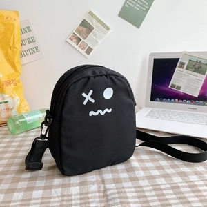 Détail d'un sac bandoulière en toile noire avec visage de dessin animé sur tissu à carreaux