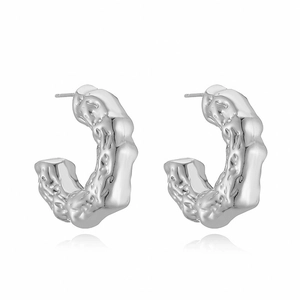 Macro shot of silver C-shaped earrings with irregular hammered texture on white background