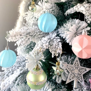 Assorted glittery Christmas tree ornaments including stars and striped baubles on snowy branches