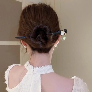 Detailed view of black wooden hair stick with rabbit charm and green jade bead tassel