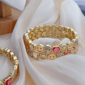 Chic gold-plated bracelet featuring pink hearts, smiley faces, and sparkling rhinestones