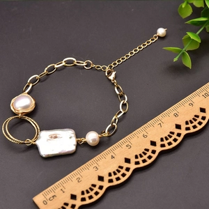 Detailed macro view of baroque pearl bracelet with gold chain and measurement ruler