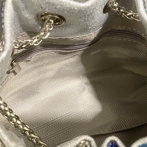 Dettaglio della borsa a secchiello argento con fodera a spina di pesce e tasca interna zip