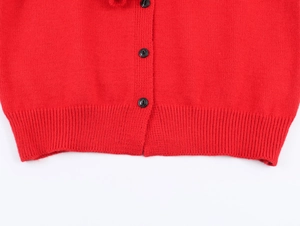 Close-up of red knit cardigan detailing fine texture, black buttons, and ribbed hemline
