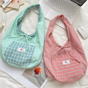 Detail of canvas tote bags in mint green and pink with checkered pockets and tie closure