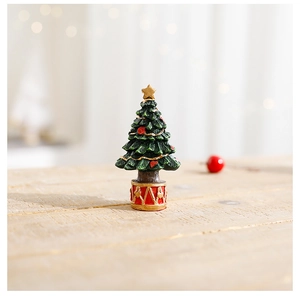 Close-up of resin mini Christmas tree with red hearts and golden base on wood