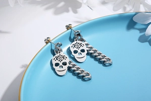Macro detail of silver stainless steel skull earrings with chunky curb chains