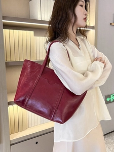 Vintage burgundy oil wax leather tote bag shown in a professional lifestyle setting
