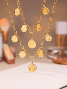 Close-up of layered gold coin pendants with Queen Elizabeth portrait on link chain