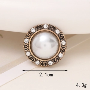 Macro shot of vintage pearl charm with bronze filigree and white rhinestones, 2.1cm diameter