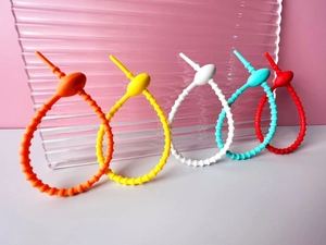 Matte silicone ring organizers in vibrant colors arranged on a textured pink background
