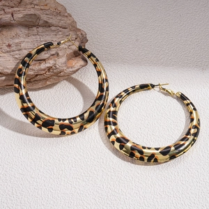 Close-up of large gold hoop earrings featuring a vibrant orange leopard print pattern