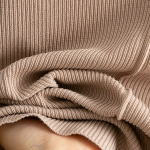 Macro detail of the light brown ribbed knit fabric showing soft texture and elasticity