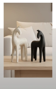 Detail of modern abstract horse statues in matte resin on a light wood surface