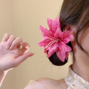 Detail view of large pink fabric lily hair clip worn on model for vacation styling
