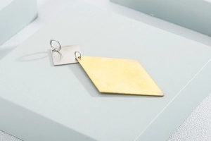 Close-up of minimalist gold rhombus and silver square geometric metal pendant charms