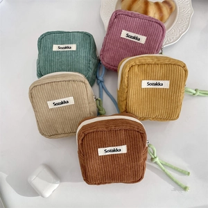 Macro detail of various corduroy cosmetic bags with zipper closure and woven lanyards