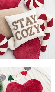 Detailed embroidery of Stay Cozy letters on beige Christmas pillow with festive decorations