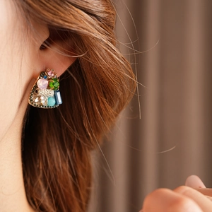 Close-up of vintage gold earrings with colorful rhinestones worn by a model