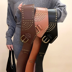 Detail of bohemian leather belts with gold studs and vintage buckles on grey knit dress