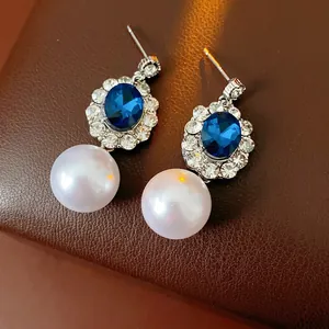 Vintage style jewelry set with round pearls and blue gemstones surrounded by crystals