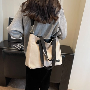 Minimalist off-white canvas tote bag with black straps and spacious interior for daily use