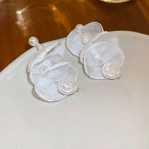 Elegant white lace flower earrings with pearls shown at a 45-degree angle on a ceramic plate