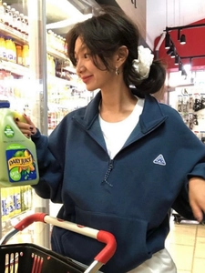 Détail du sweat à col zippé en coton bleu marine avec broderie sur la poitrine et logo