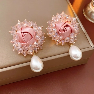 Detail of vintage earring featuring pink ribbon rose, crystal ring, and drop pearl