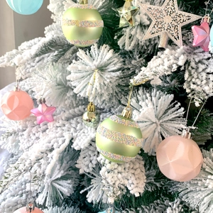 Detailed view of colorful star and geometric Christmas ornaments on a snowy flocked tree
